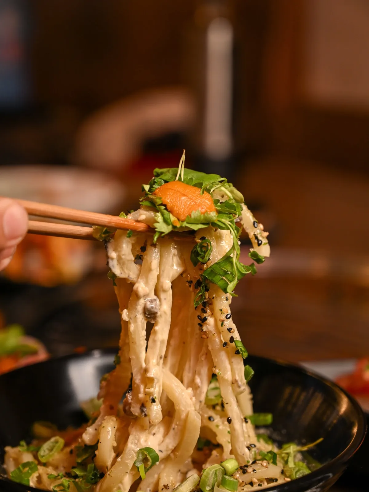 Chopsticks lifting udon topped with fresh uni